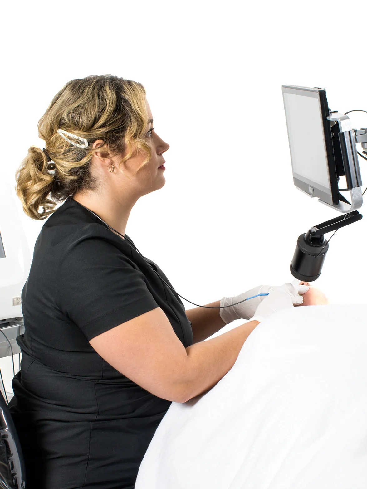 Practitioner treating a patient while watching a magnified view on a high-definition screen