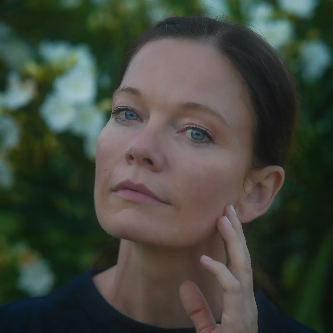 Woman in her forties touching her cheek in soft light