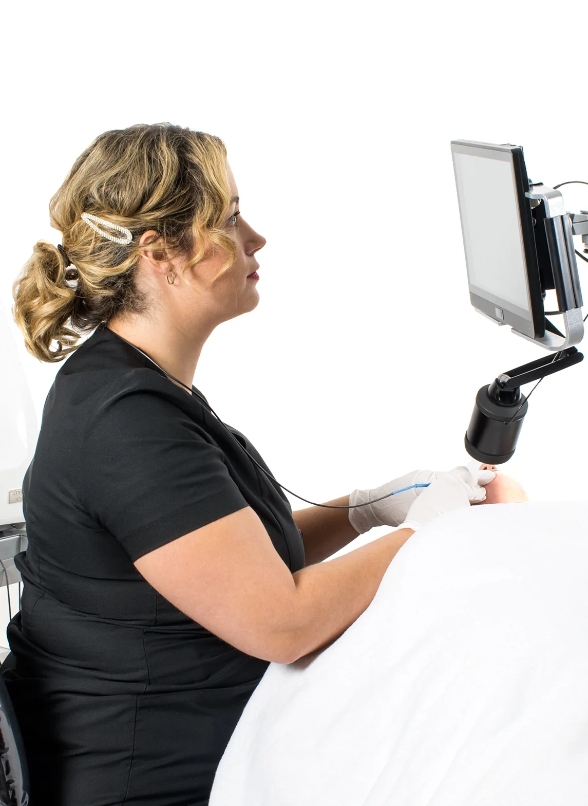 Electrologist seated upright, treating a patient with the Opti-Vizion Flip screen and camera