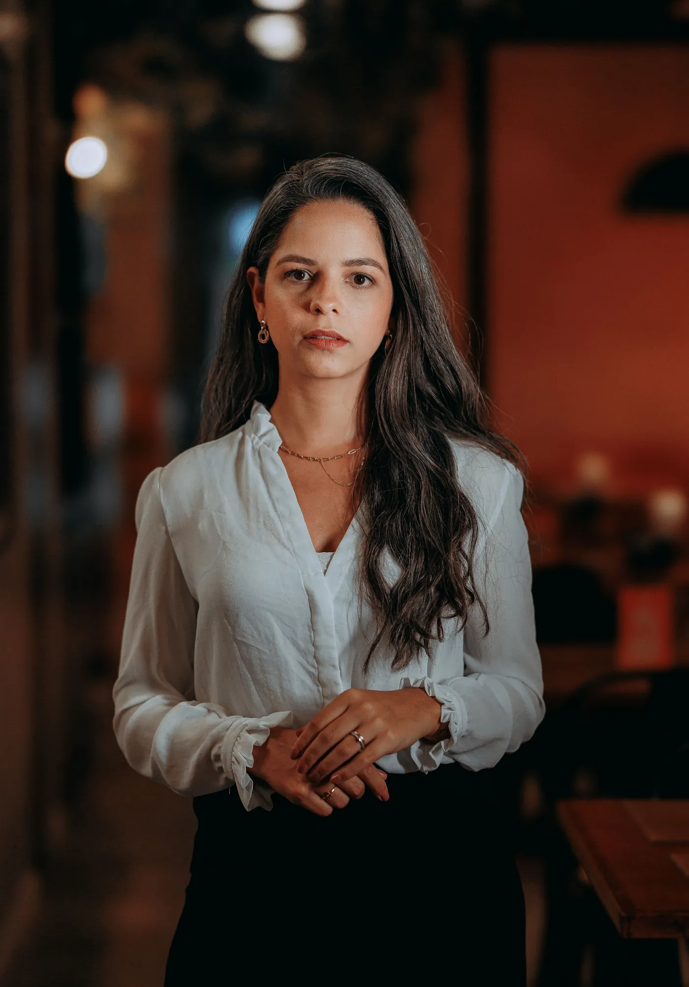 Confident woman standing with hands clasped