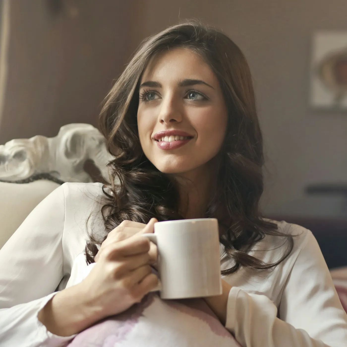 Smiling woman relaxing at home with a warm drink