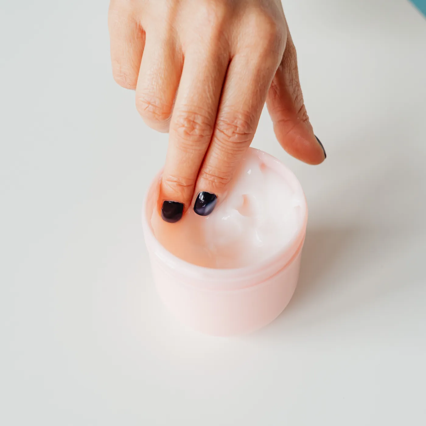 Hand reaching into a jar of soothing cream