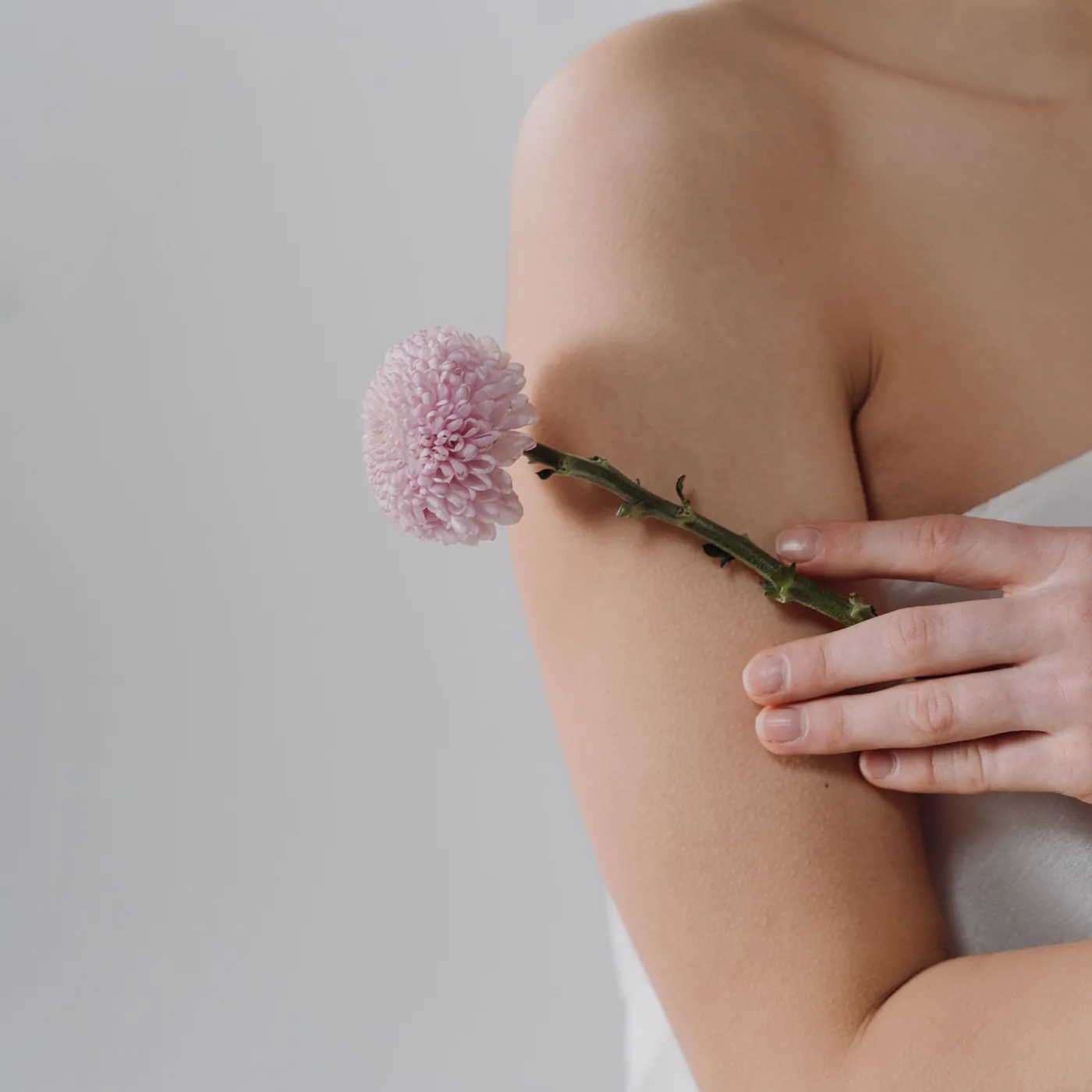 Woman holding a flower against her smooth arm