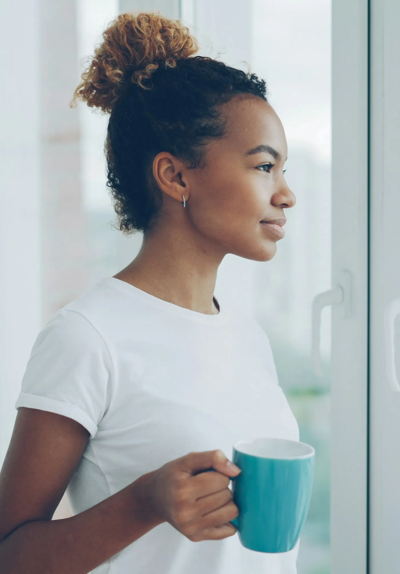 Woman relaxing at home with a cup of tea by the window